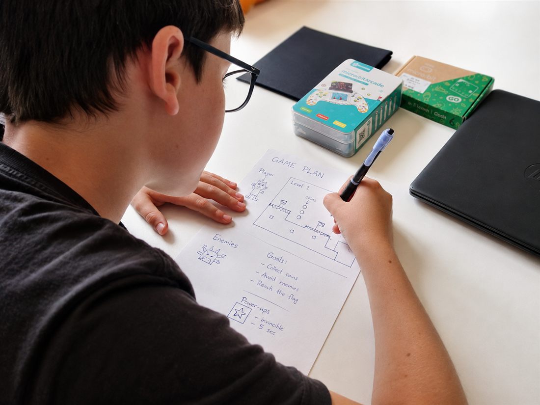 Niño diseñando en papel el plan de su videojuego antes de programar