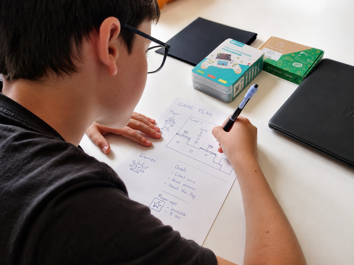Niño diseñando en papel el plan de su videojuego antes de programar